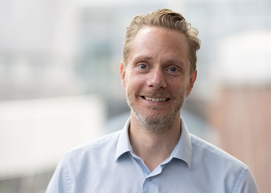Portrait of Mathias Bjuhr with blurry buildings in the background.