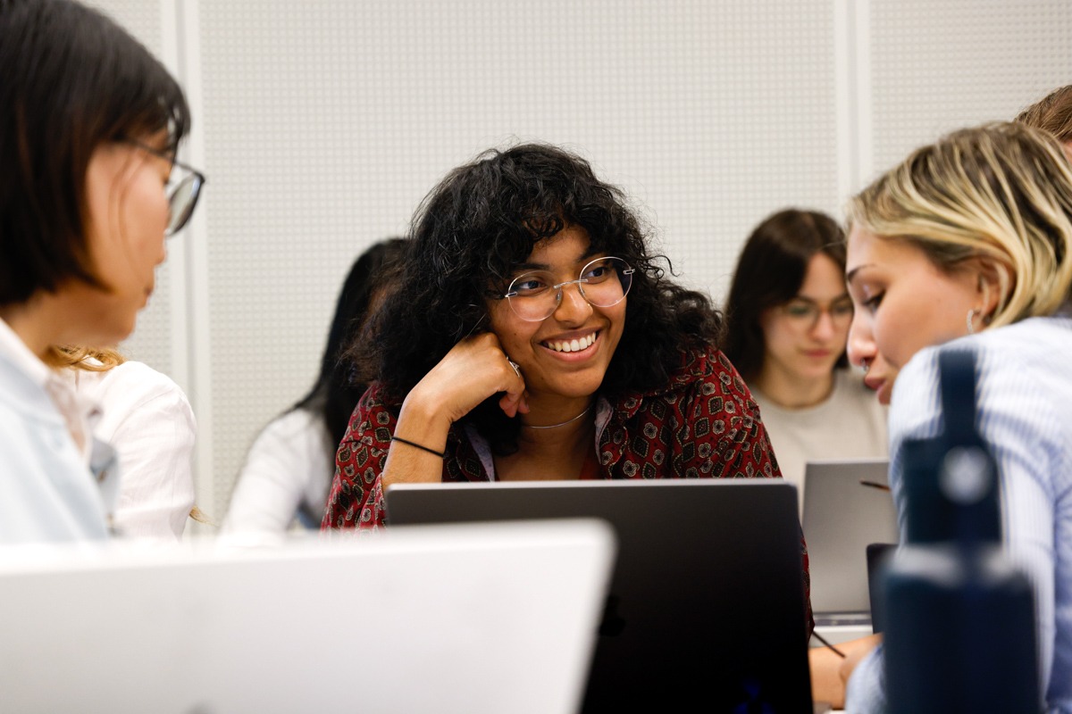 Participants at the course sitting in front of computers, discussing with each other and smiling.